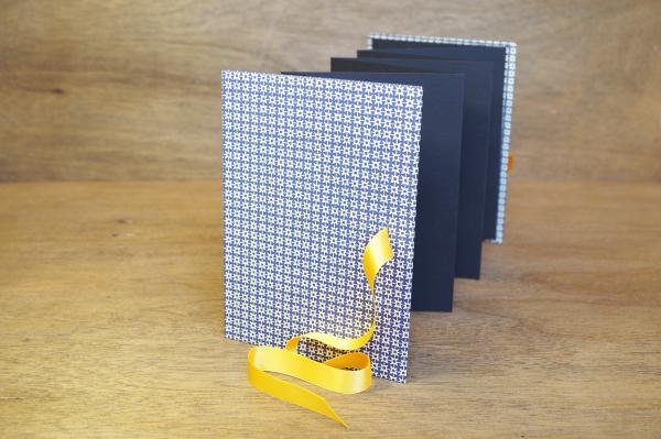 Leporello standing, black zig-zag pages, yellow ribbon